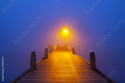 Jetty on a foggy morning at dawn photo