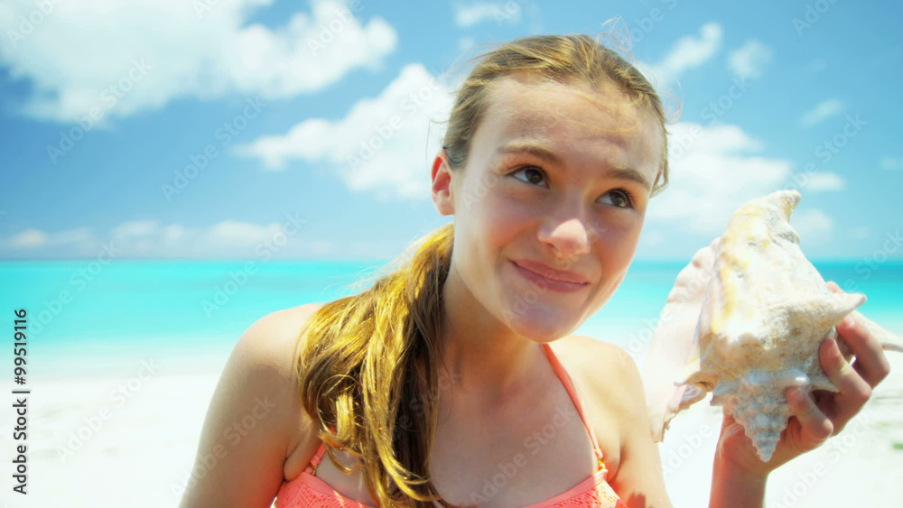 Portrait of smiling Caucasian girl on a beach holding a conch shell