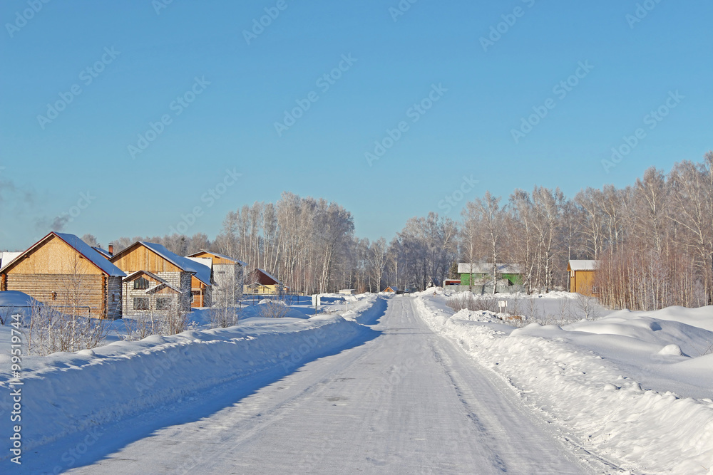 Winter road through the forest to the village