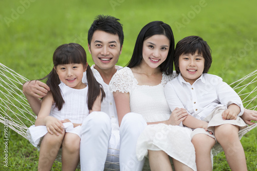 Happy young family sitting in a hammock outdoors