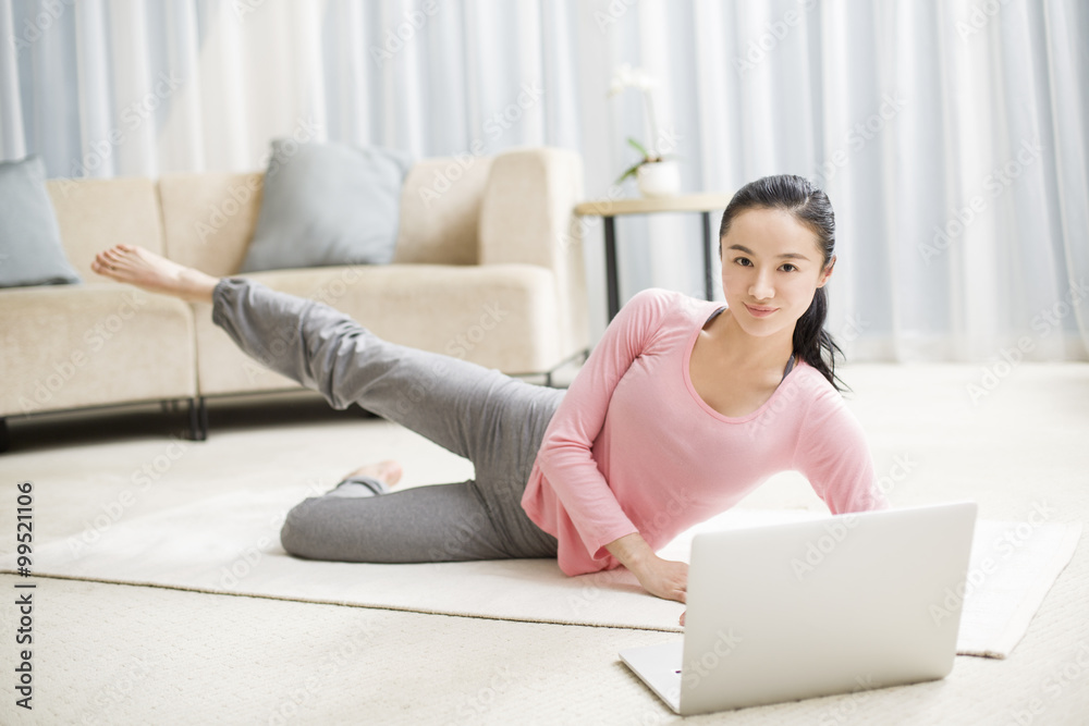 Young woman practicing yoga with laptop in living room Young woman practicing yoga with laptop in living room