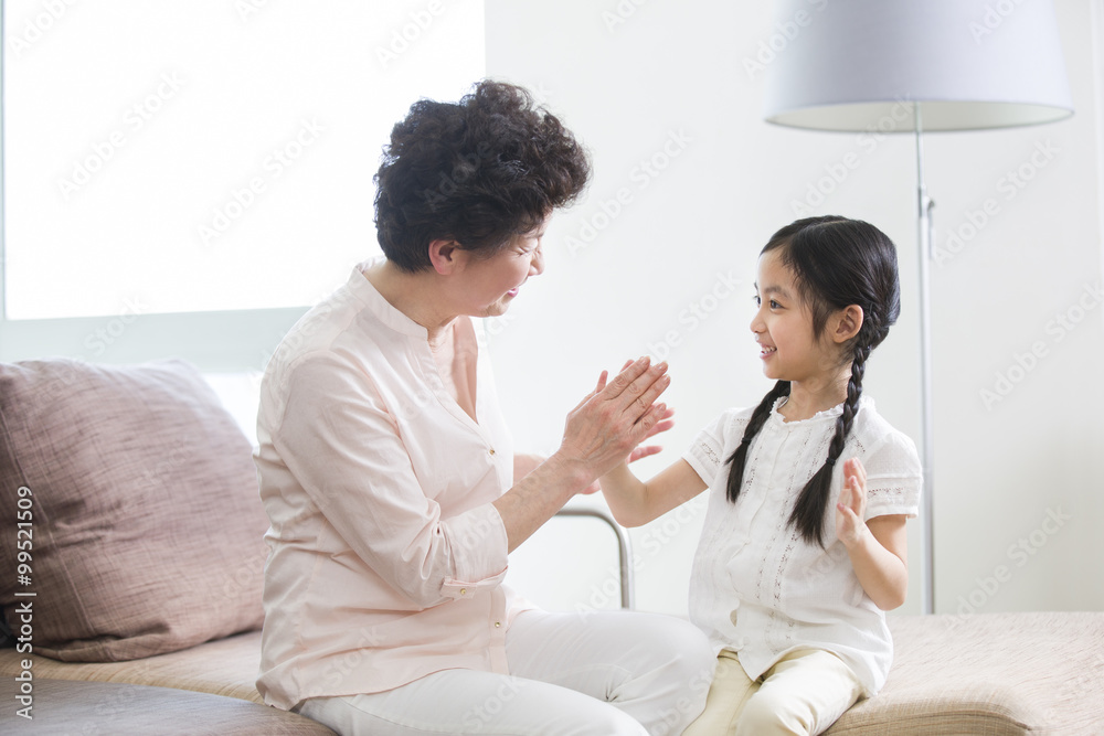 Happy grandmother and granddaughter playing clapping game Happy grandmother and granddaughter playing clapping game