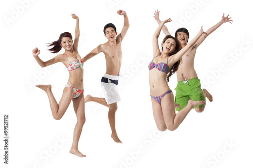 Young men and young women in swimsuit jumping in mid-air