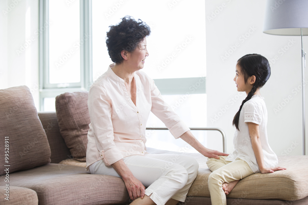 Happy grandmother and granddaughter sitting in sofa Happy grandmother and granddaughter sitting in sofa