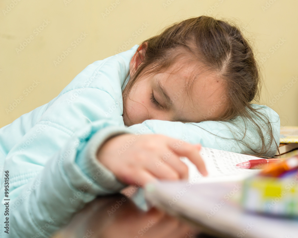 Naklejka premium Young girl falling asleep doing homework