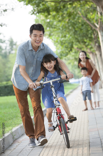 Young father teaching his daughter to ride a bicycle