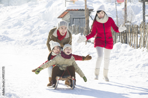 Photography Happy family playing with sled in the snow