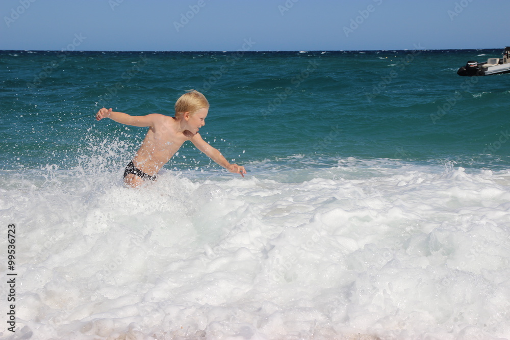 Boy playing with the waves of the sea, Italy, Sardinia