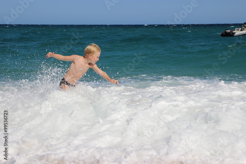 Boy playing with the waves of the sea, Italy, Sardinia
