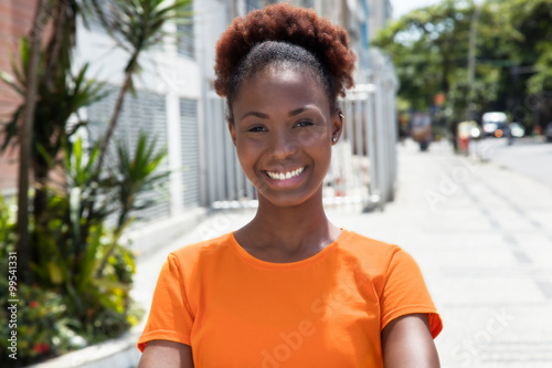 Schöne afrikanische Frau mit orangefarbenen Shirt in der Stadt © Daniel Ernst