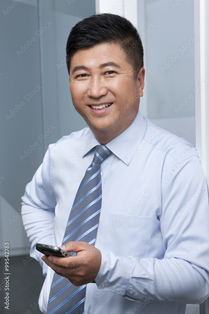 Smiling businessman holding his mobile phone Smiling businessman holding his mobile phone