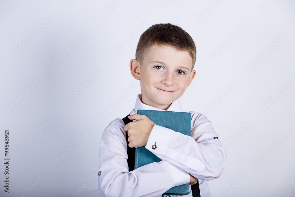 Smiling Portrait of a cute little school boy loving to learn, holding with hands a book and wearing glasses isolated over yellow background. Smiling Portrait of a cute little school boy loving to learn, holding with hands a book and wearing glasses isolated over yellow background.