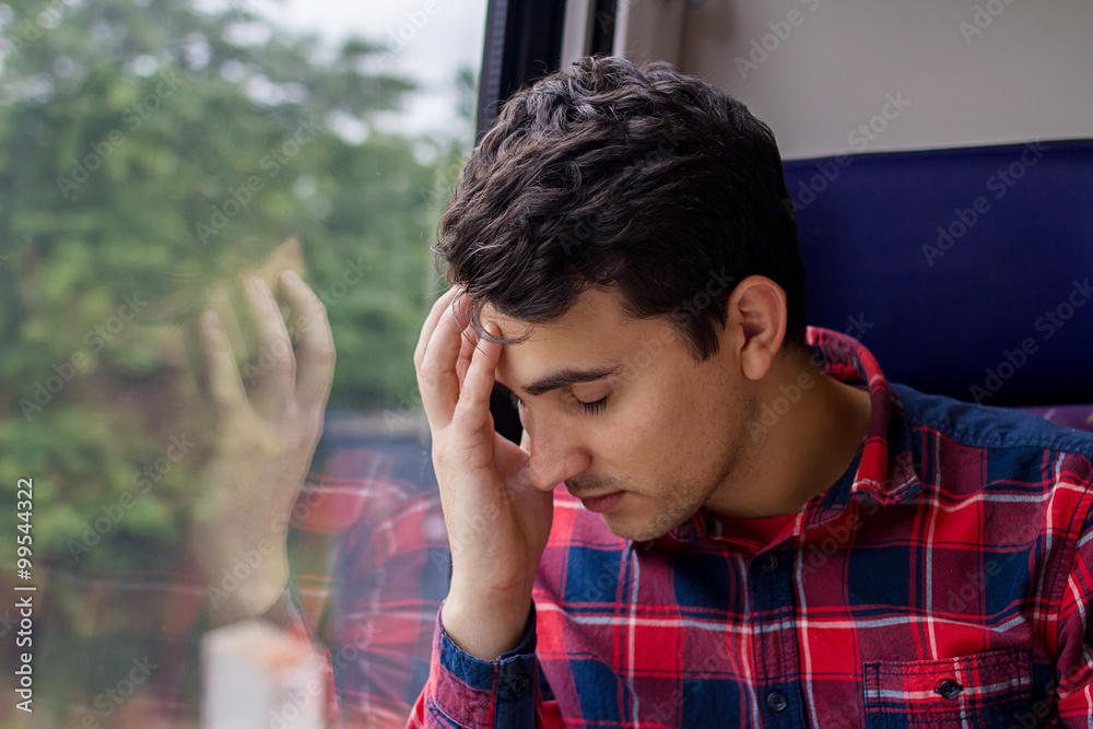 Depressed young student man traveling home by train.Sad upset man traveling by train. Depressed young student man traveling home by train.Sad upset man traveling by train.