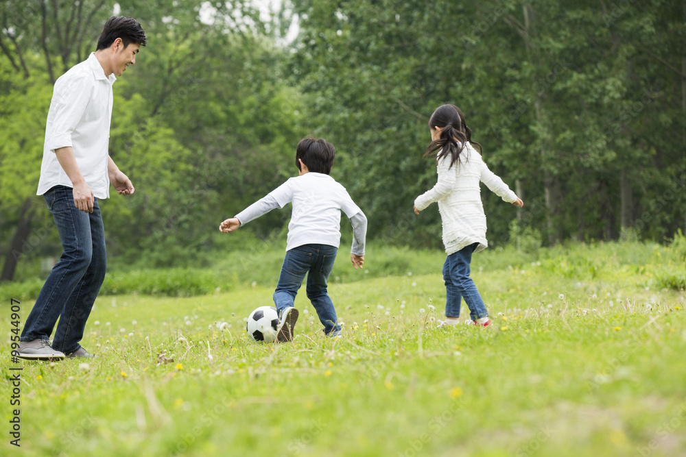 Happy father and children playing football together Happy father and children playing football together