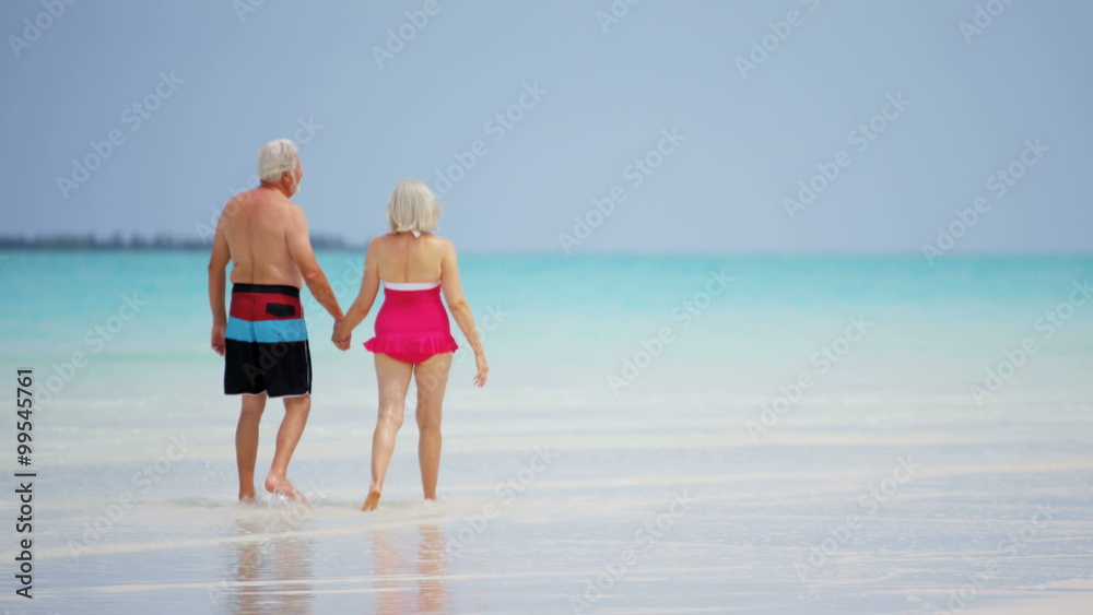 Mature Caucasian couple in swimwear outdoors together on tropical beach Mature Caucasian couple in swimwear outdoors together on tropical beach