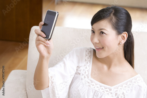 Asian woman playing with cell phone on a sofa