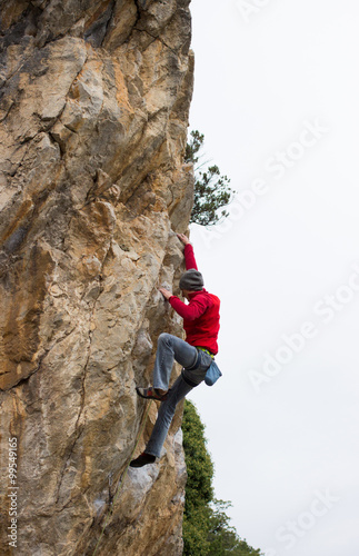 Young male climber hanging on a cliff with a rope.