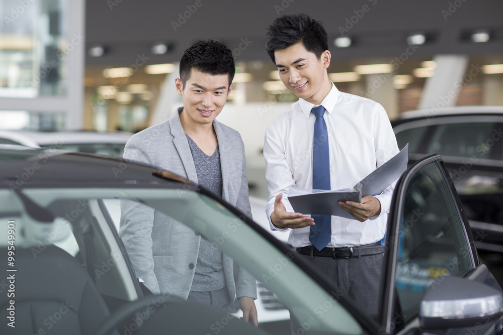 Young man choosing car in showroom Young man choosing car in showroom