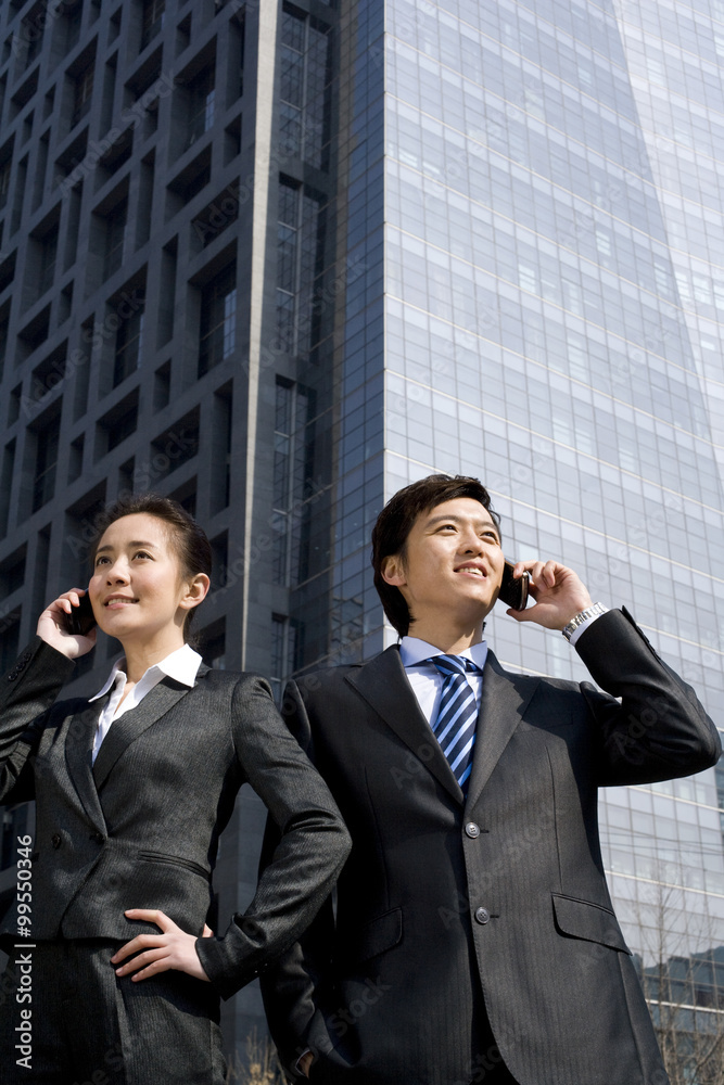 Business partners talking on phones, back to back Business partners talking on phones, back to back