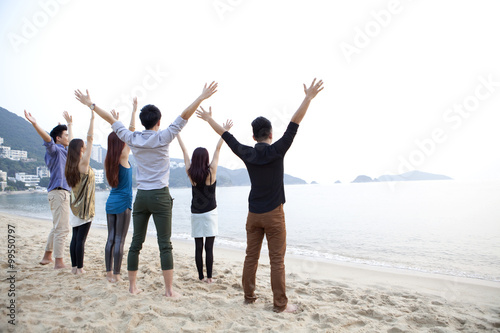 Rear view of happy young people raising hands on the beach of Repulse Bay, Hong Kong