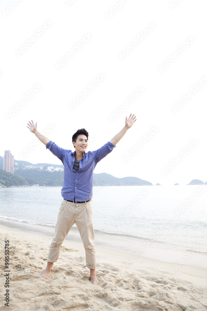 Cheerful young man arms outstretched on the beach of Repulse Bay, Hong Kong Cheerful young man arms outstretched on the beach of Repulse Bay, Hong Kong