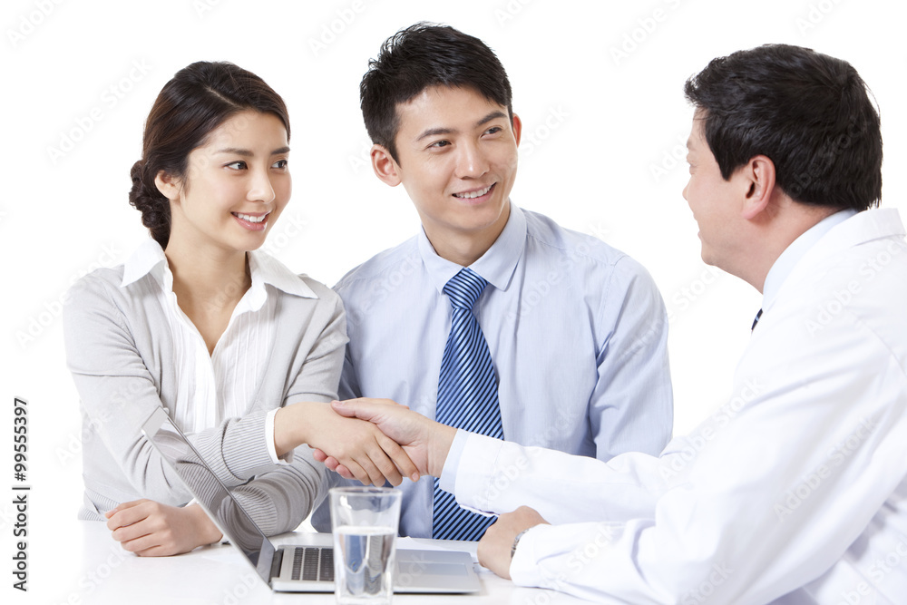 Cheerful young couple shaking hands with doctor