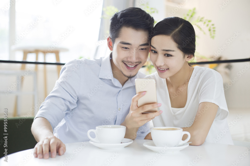 Happy young couple using smart phone in coffee shop Happy young couple using smart phone in coffee shop