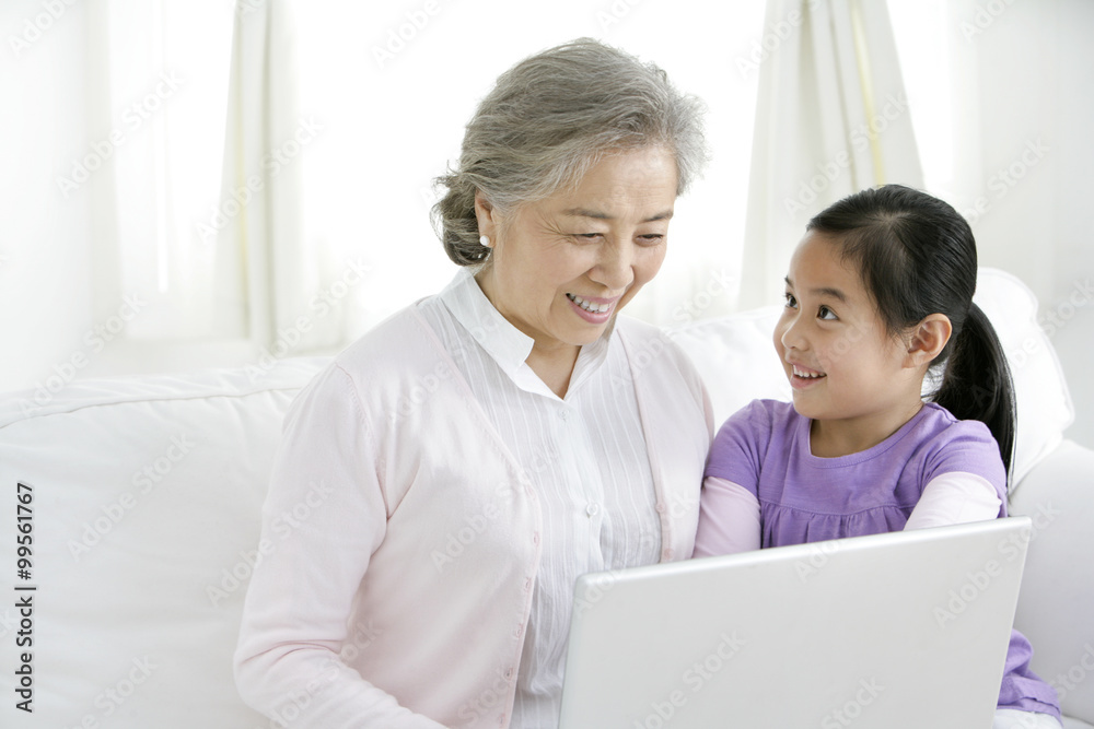 Chinese grandmother with grandaughter using a laptop