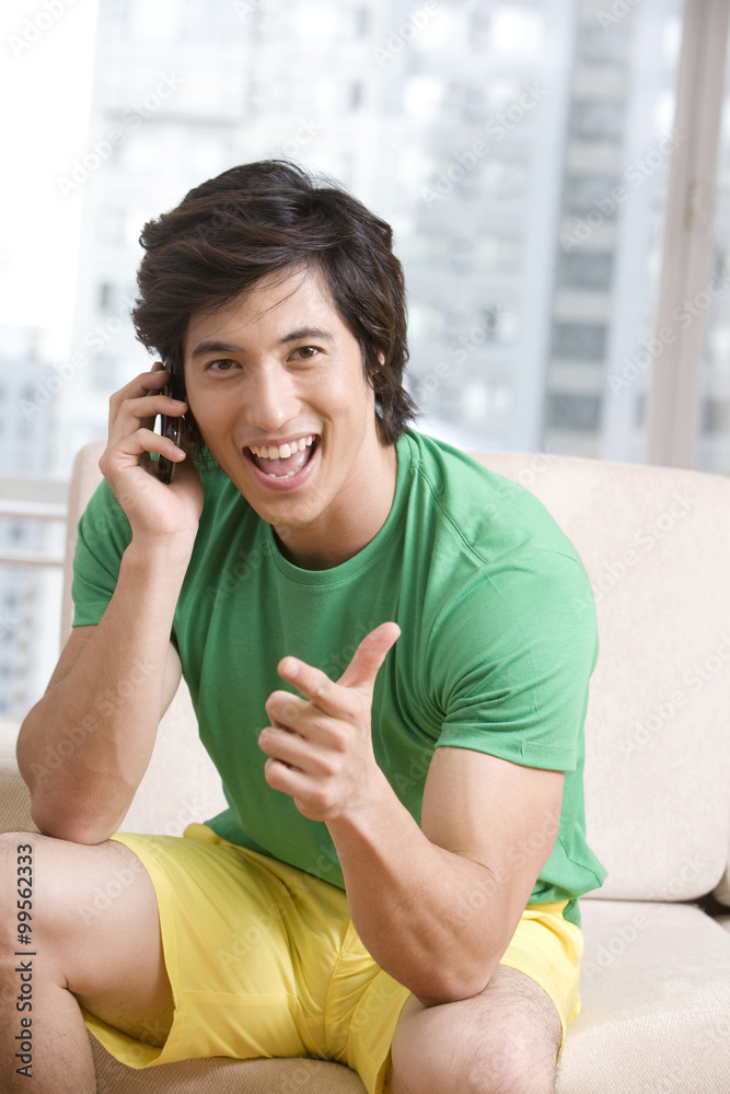 Asian man talking on the phone on a sofa