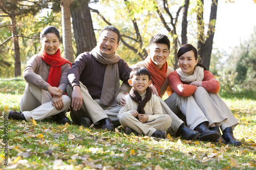 Family sitting on the grass in a park in Autumn