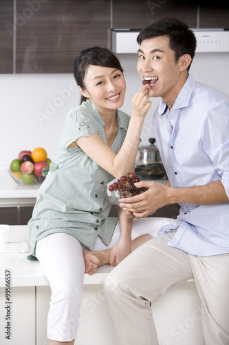 Woman feeding man grapes in the kitchen