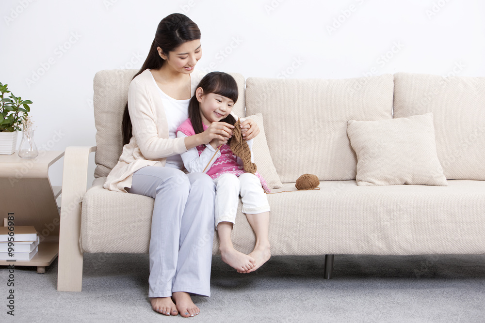 Happy mother teaching little daughter knitting at home Happy mother teaching little daughter knitting at home