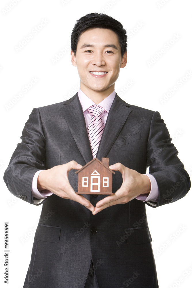Businessman holding a small wooden model home Businessman holding a small wooden model home