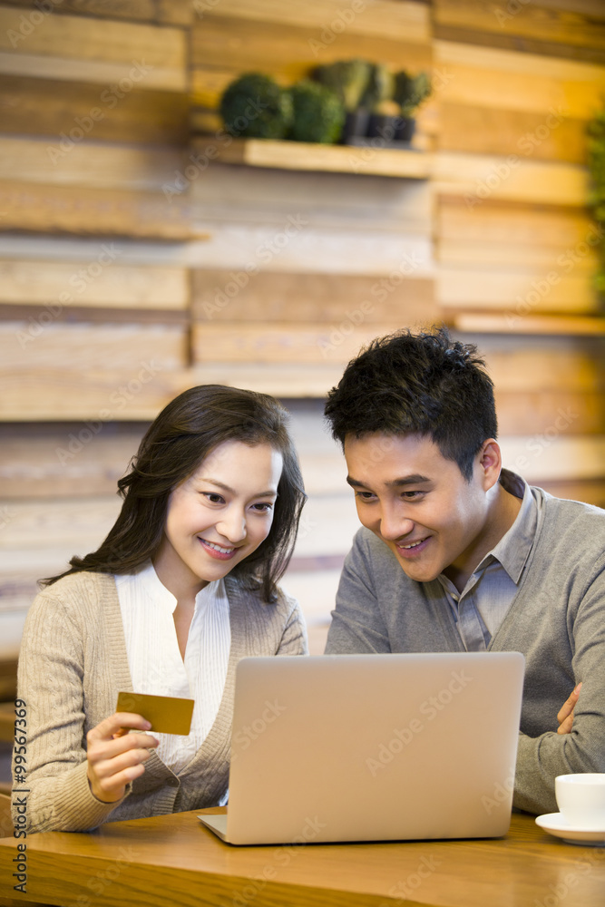 Cheerful young couple shopping online in cafe