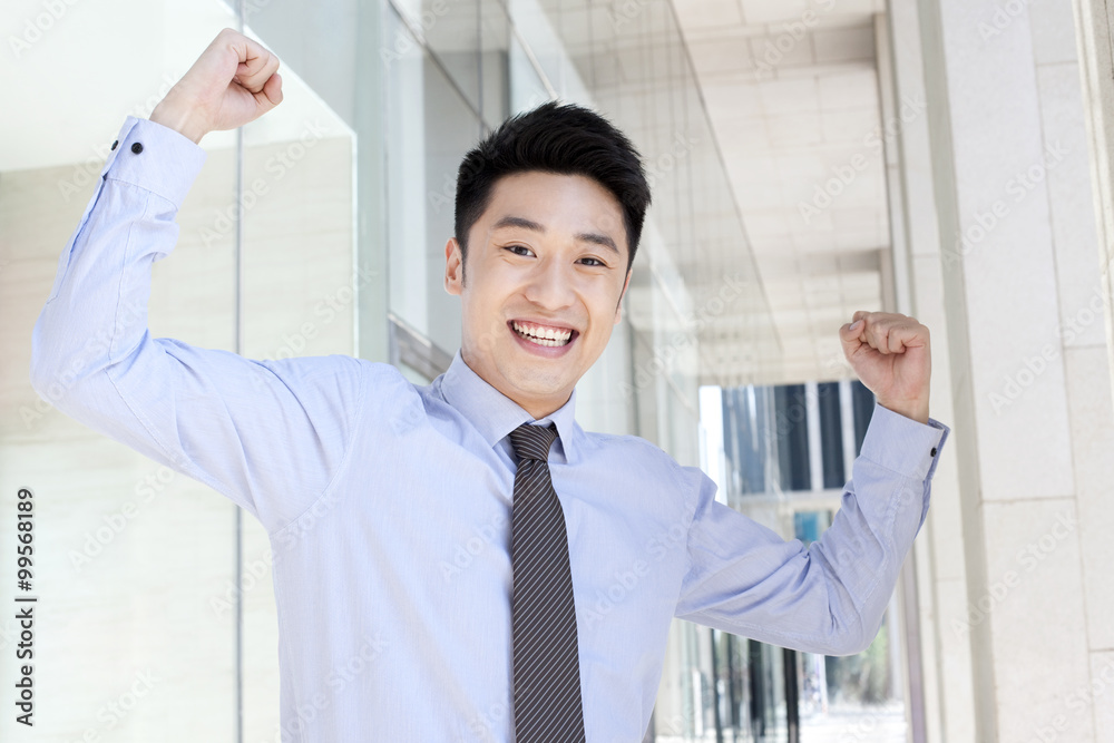 Excited young businessman celebrating in downtown district Excited young businessman celebrating in downtown district