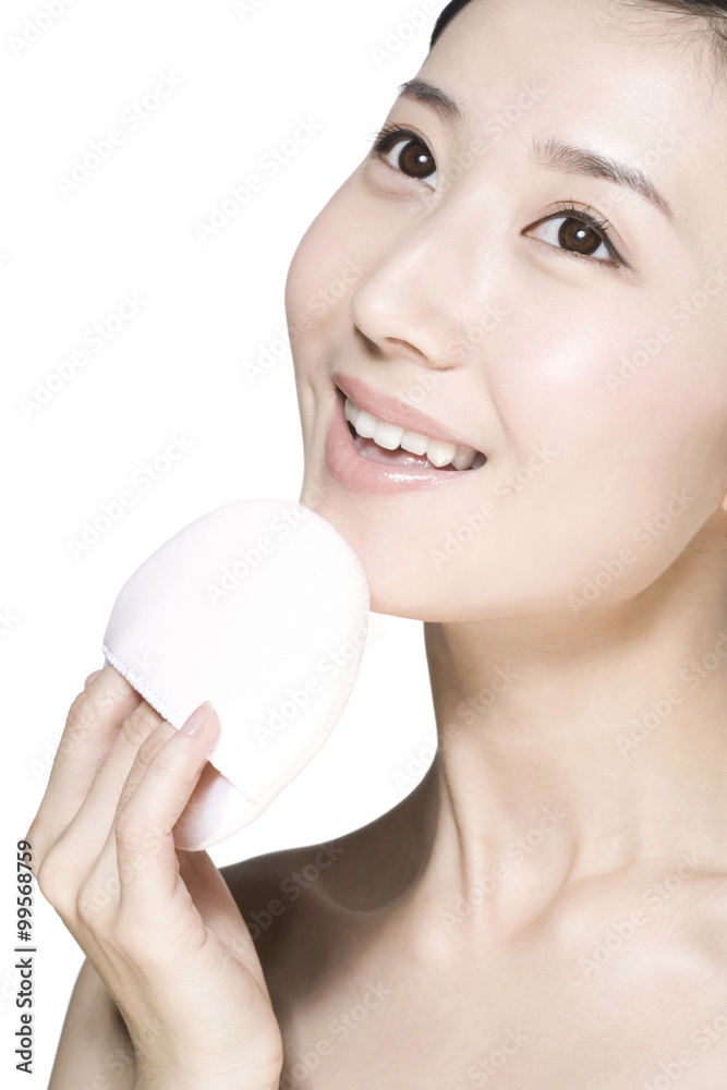 Beauty shot of a young woman holding a powder puff Beauty shot of a young woman holding a powder puff
