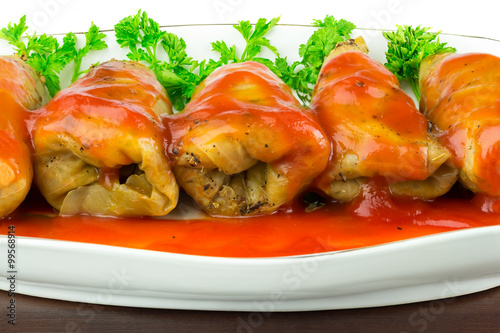 Cabbage roll with tomato sauce and parsley in plate, close-up photo