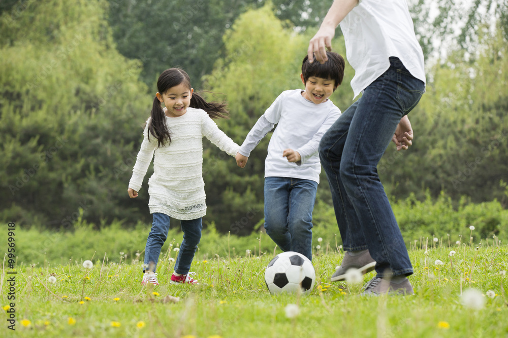 Happy father and children playing football together Happy father and children playing football together