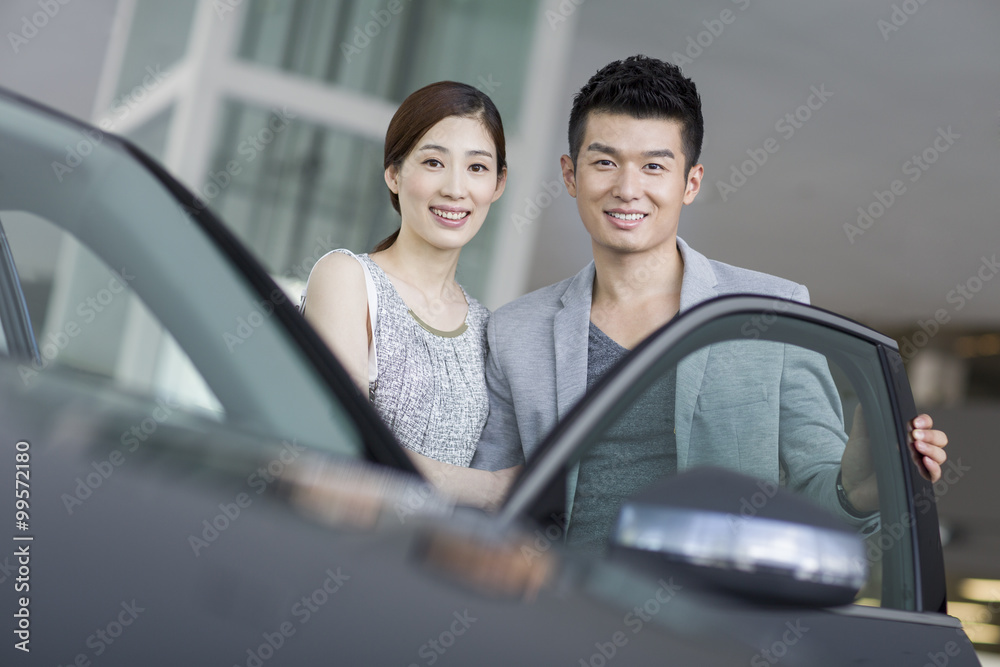Young couple choosing car in showroom Young couple choosing car in showroom