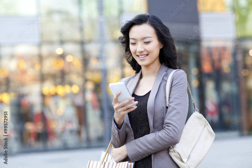 Happy young woman with shopping bags using smartphone Happy young woman with shopping bags using smartphone