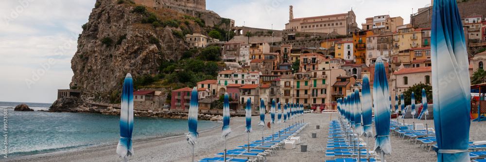 Blue umbrella and beachchair at the beach in front of small italian