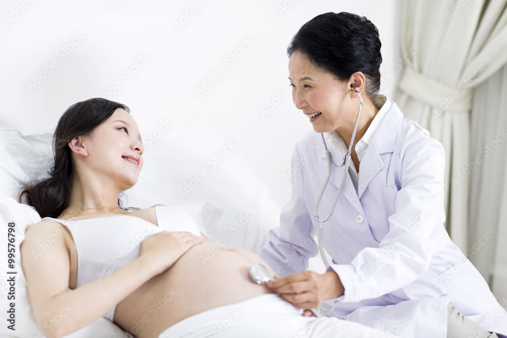 Doctor examining pregnant woman at home
