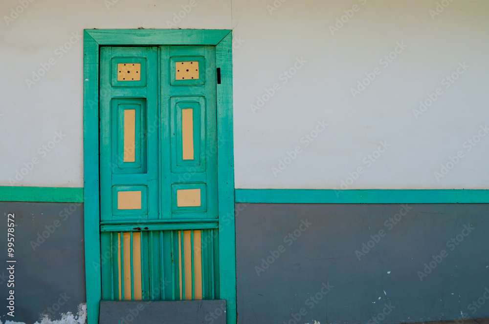 Yellow turquoise green wooden door of a colonial house front