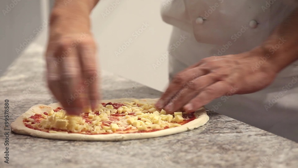 Unrecognizable man putting cheese topping on his pizza base Unrecognizable man putting cheese topping on his pizza base