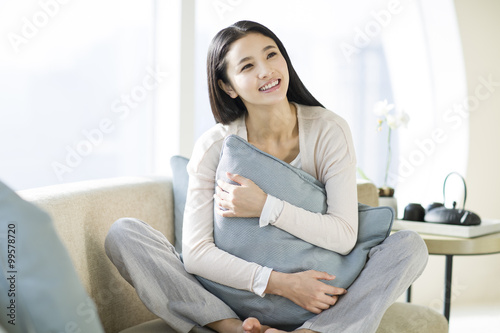 Happy young woman sitting on sofa Free Download Happy young woman sitting on sofa - GFXLoad