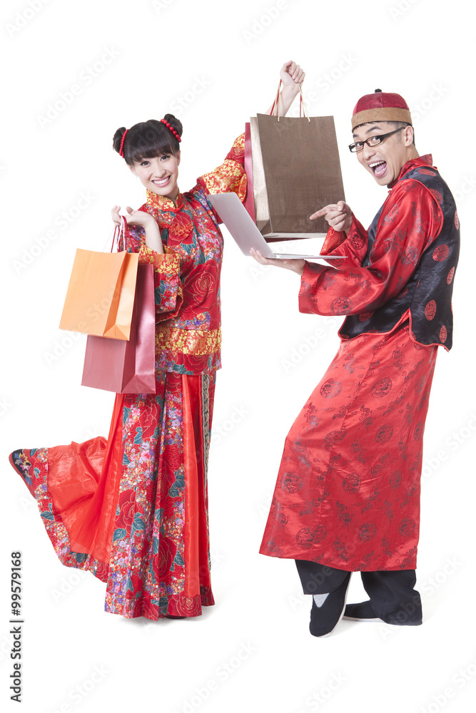 Excited young couple in Tang suit holding shopping bags and laptop Excited young couple in Tang suit holding shopping bags and laptop