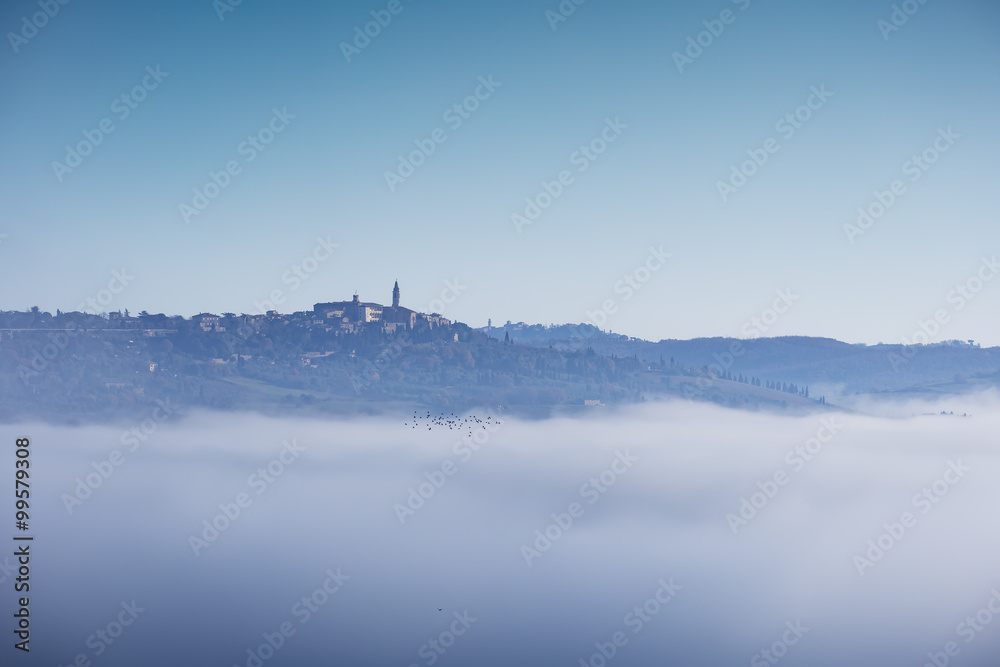 Tuscany, Pienza medieval village, bird flock and fog. Siena, Ita