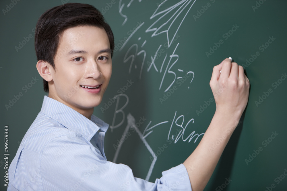 Professional male teacher writing on blackboard