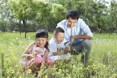 Happy family observing plants with magnifying-glasses