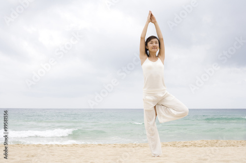 A woman practicing yoga at the beach